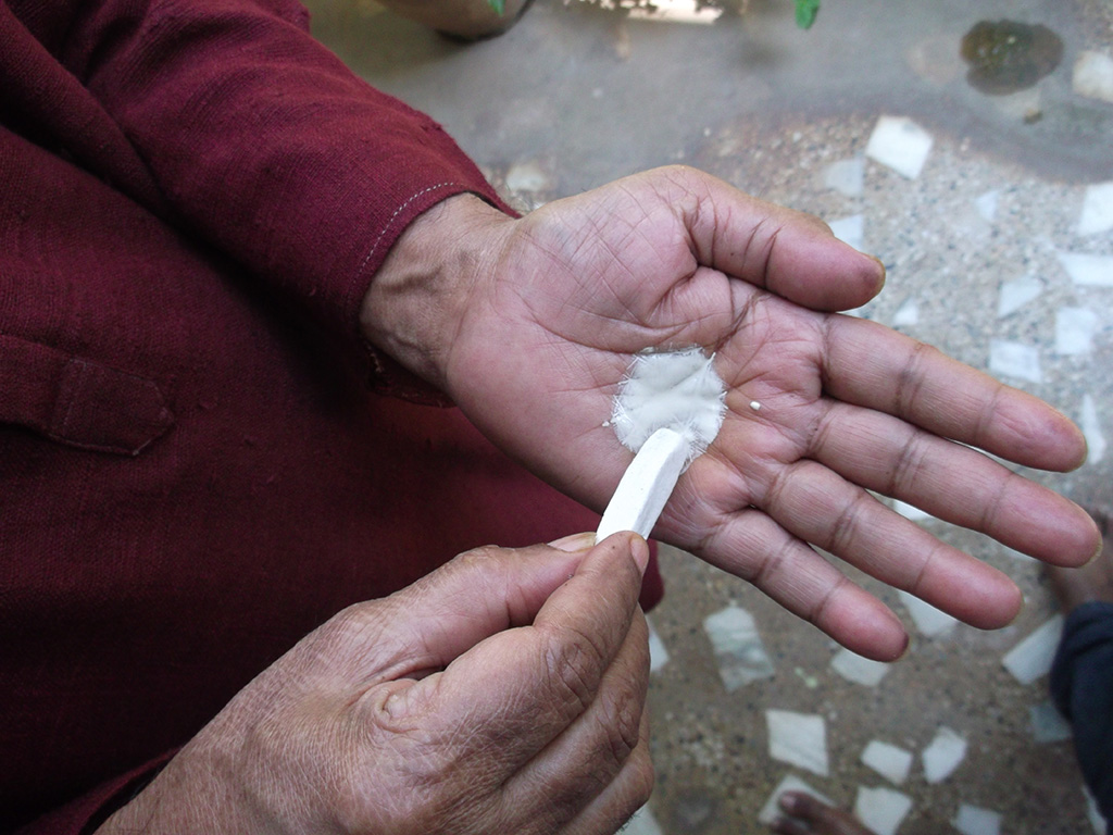 Rubbing white stone on the wet palm to form the white paste.