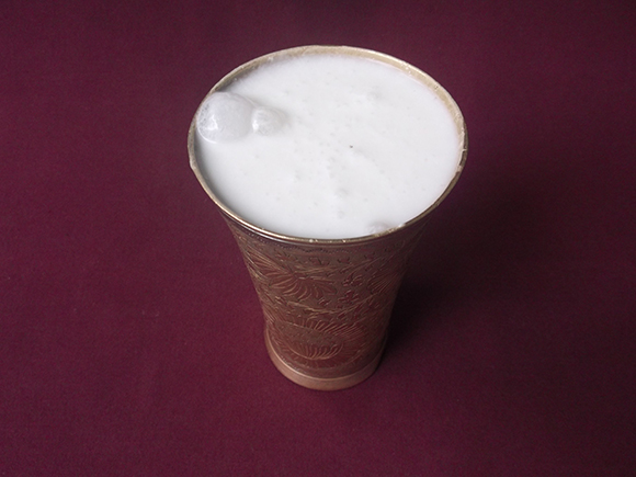 Large brass lassi glass with sweet lassi and cream.