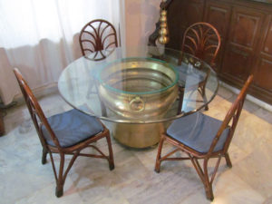 Huge antiques brass gangalam that serves as a base of the dining table with a glass top