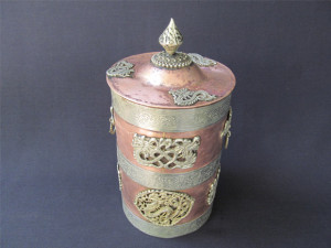Mystical copper vessel with 3 white metal strips, dragon embellishments and the lid with the knob –an angle view