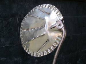Hand –held brass fan showing the design joining the leaves and boarder design around the edge of the fan