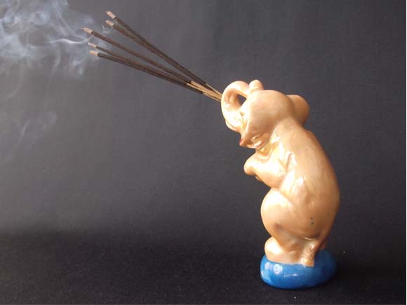 Rear view of the elephant holding incense sticks with curling smoke