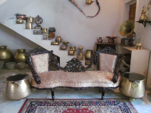 A reconditioned antique Portuguese protocol sofa matched with two old brass vessels repurposed as peg tables with glass top