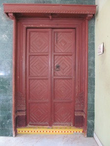 Antique main door with carved frame,projected canopy,brass handle, locking chain and turmeric yellow threshold