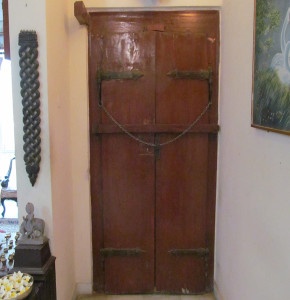 Back side view of the door with wooden plank across the door and heavy chain