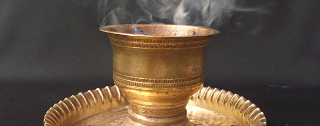 Sambrani smoke from charcoal fire in brass pot.